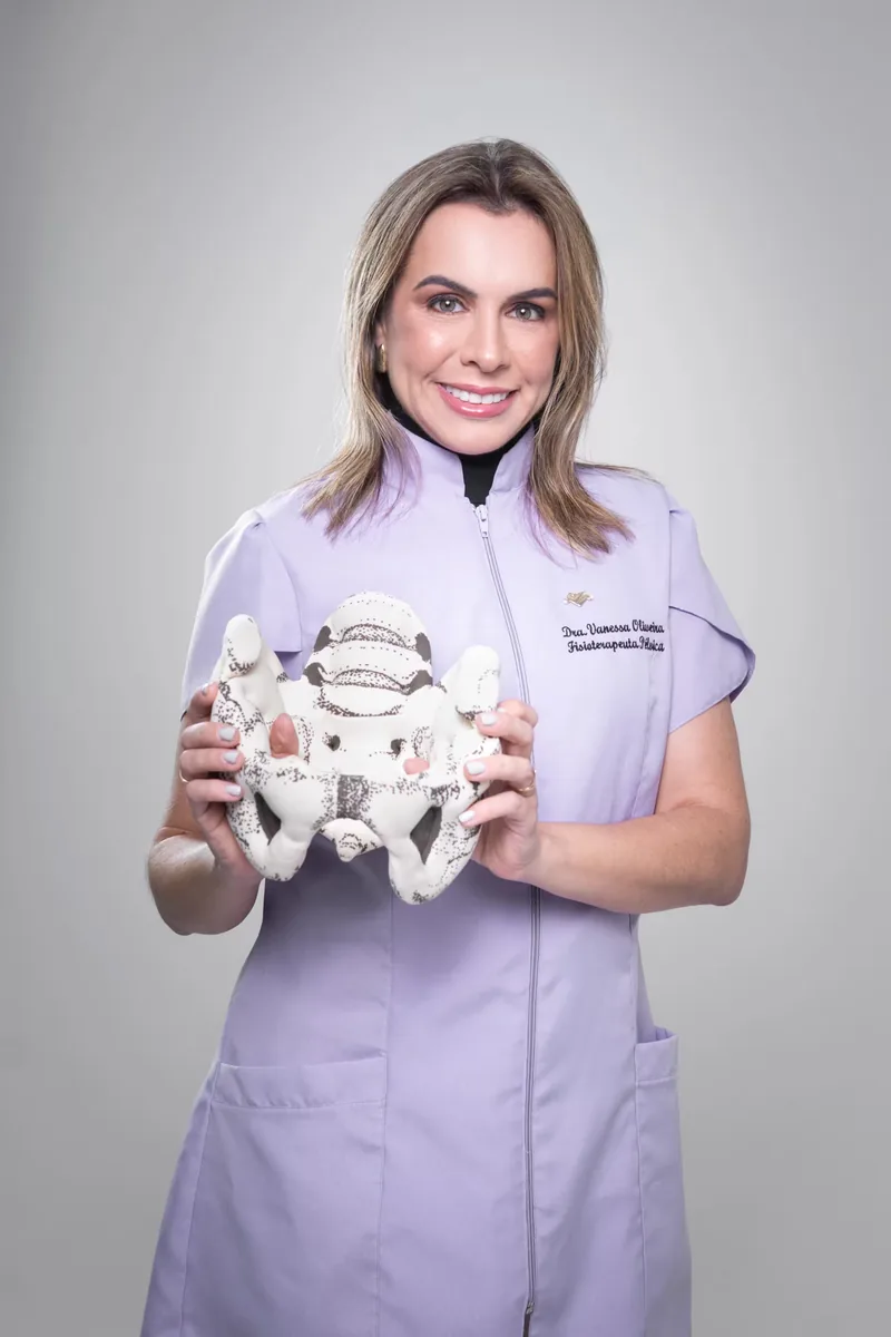 Dra. Vanessa Oliveira de uniforme lilás com um modelo anatômico da pelve